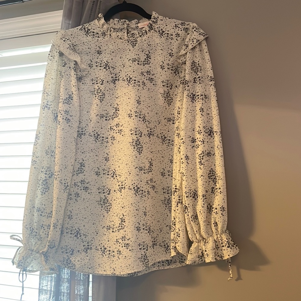 Cream blouse with black speckle pattern.